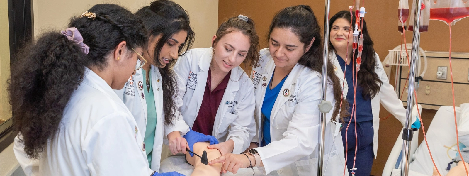 SOPM students in hospital bed assisting patient.