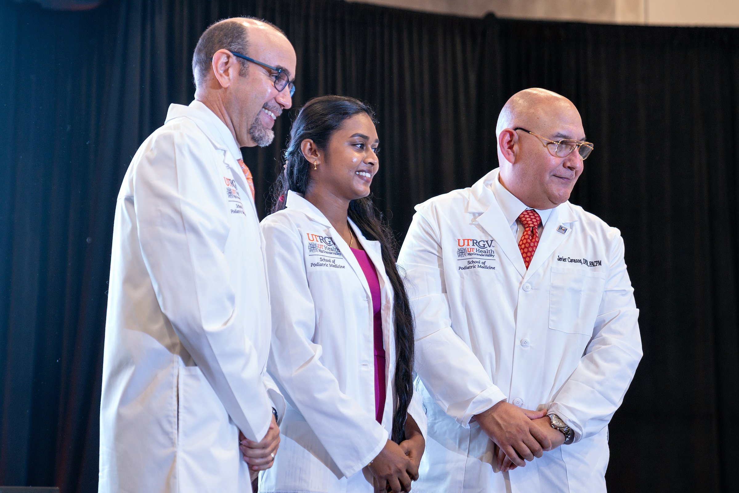 SOPM faculty posing on stage with SOPM student.