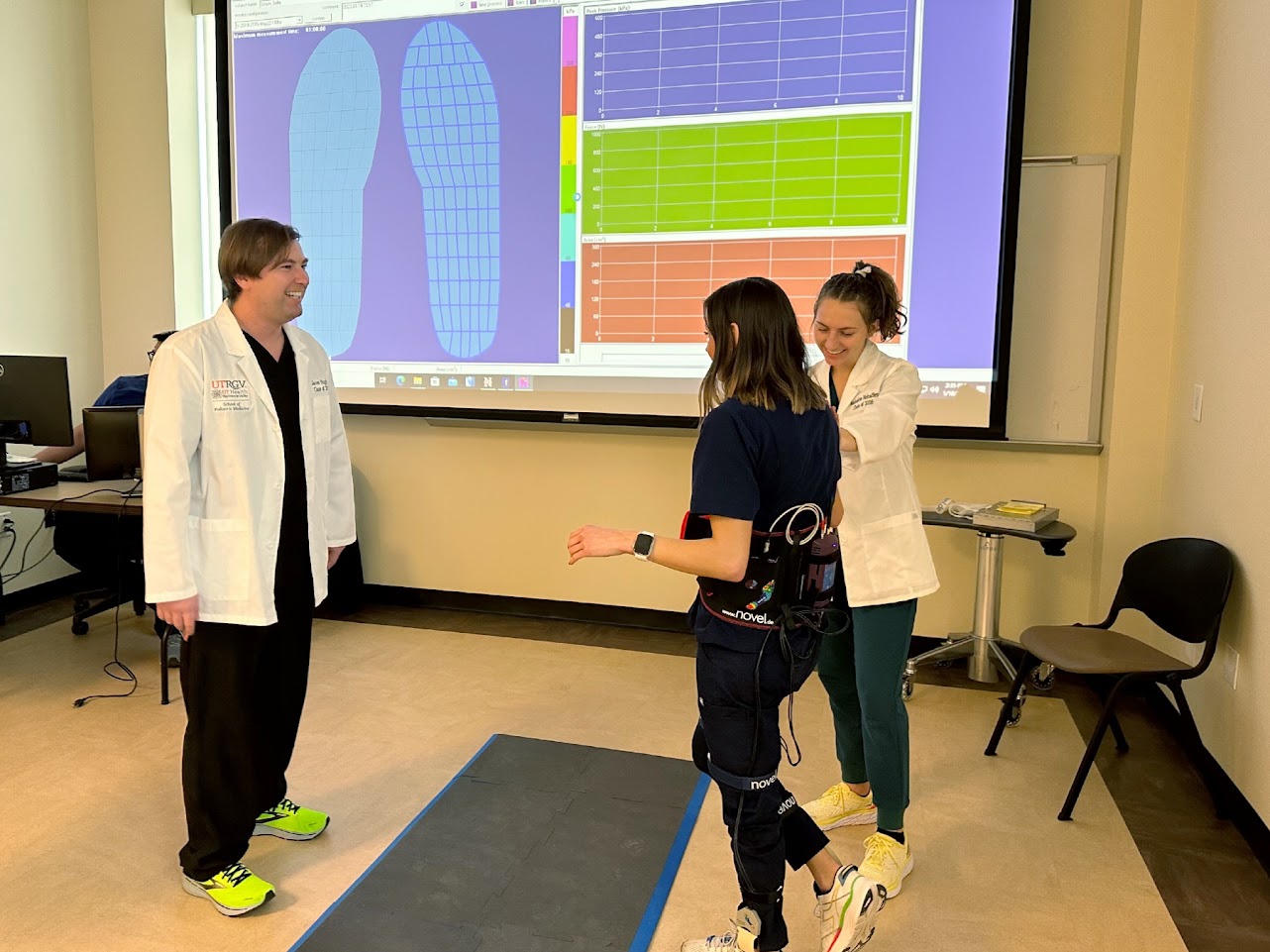 SOPM students in white coats helping patient walk.