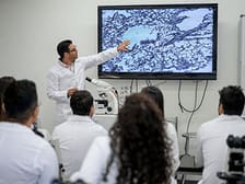 Faculty member presenting information on a digital screen to a group of students. 