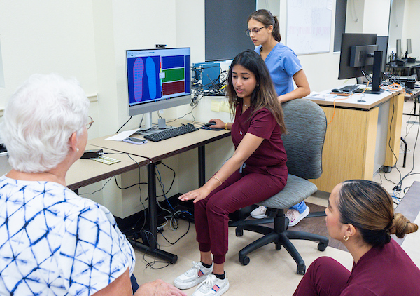 SOPM students assisting a patient to walk.