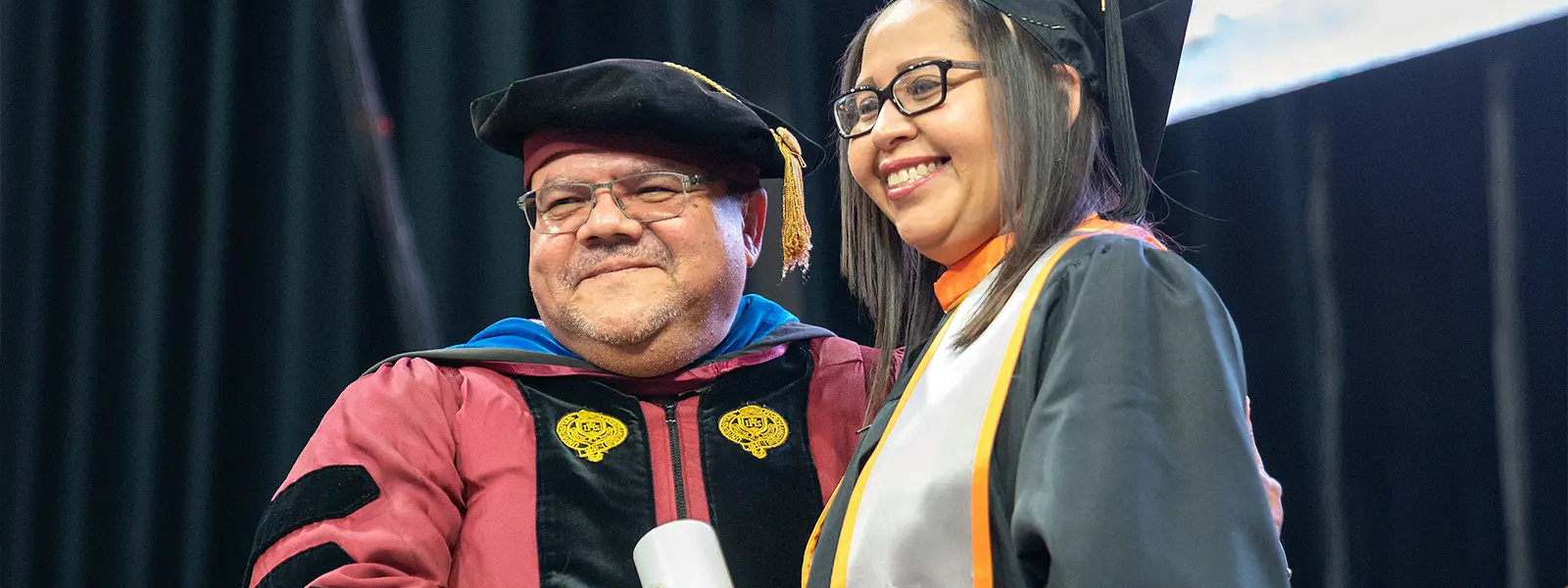 gradudate posing with the dean of SSW after accepting her degree