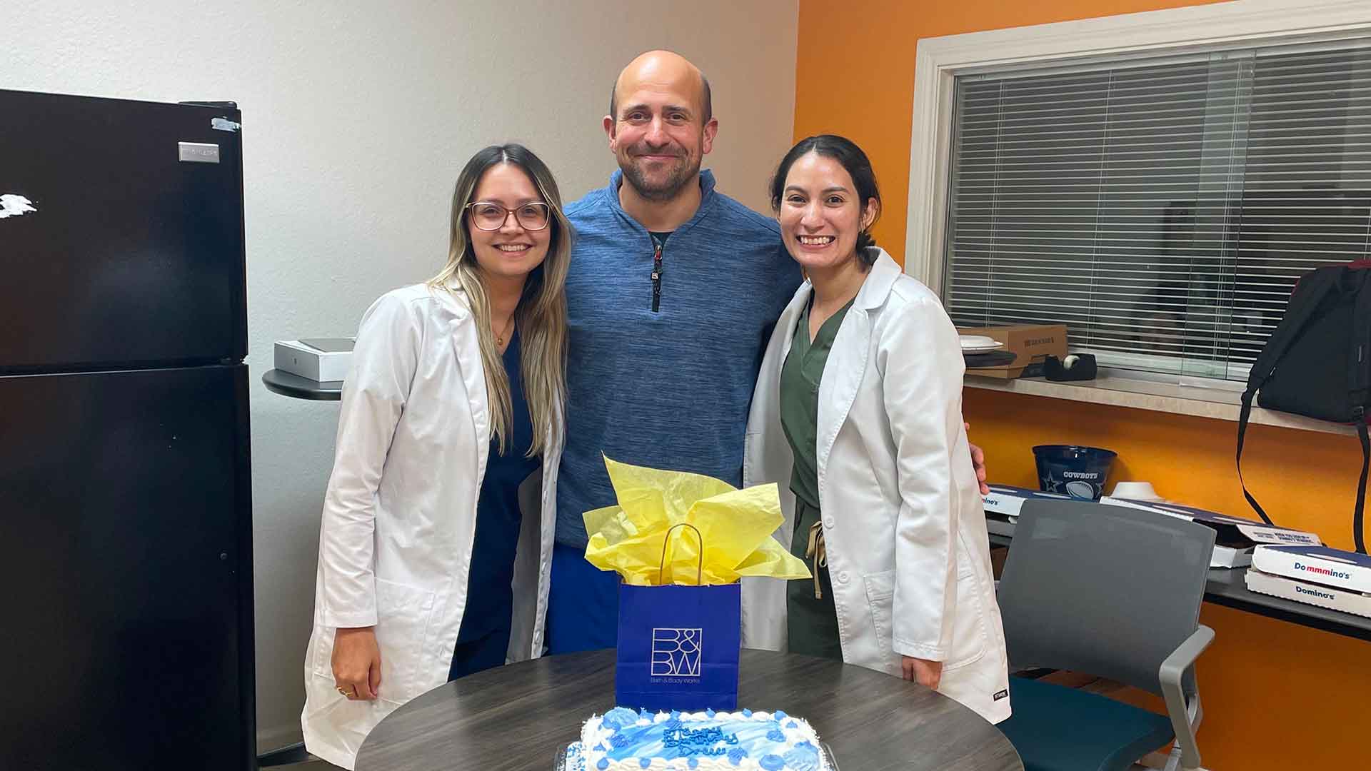 Residents celebrate cake, and gift during a residency program recognition event.