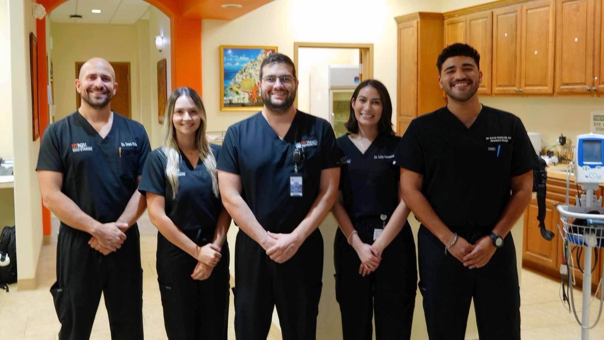 UTRGV residents in scrubs gather for a group portrait in a clinical setting.