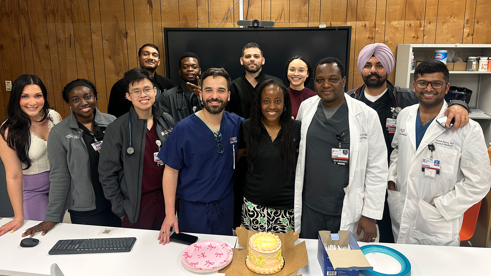 A group of smiling medical professionals stand around a cake.