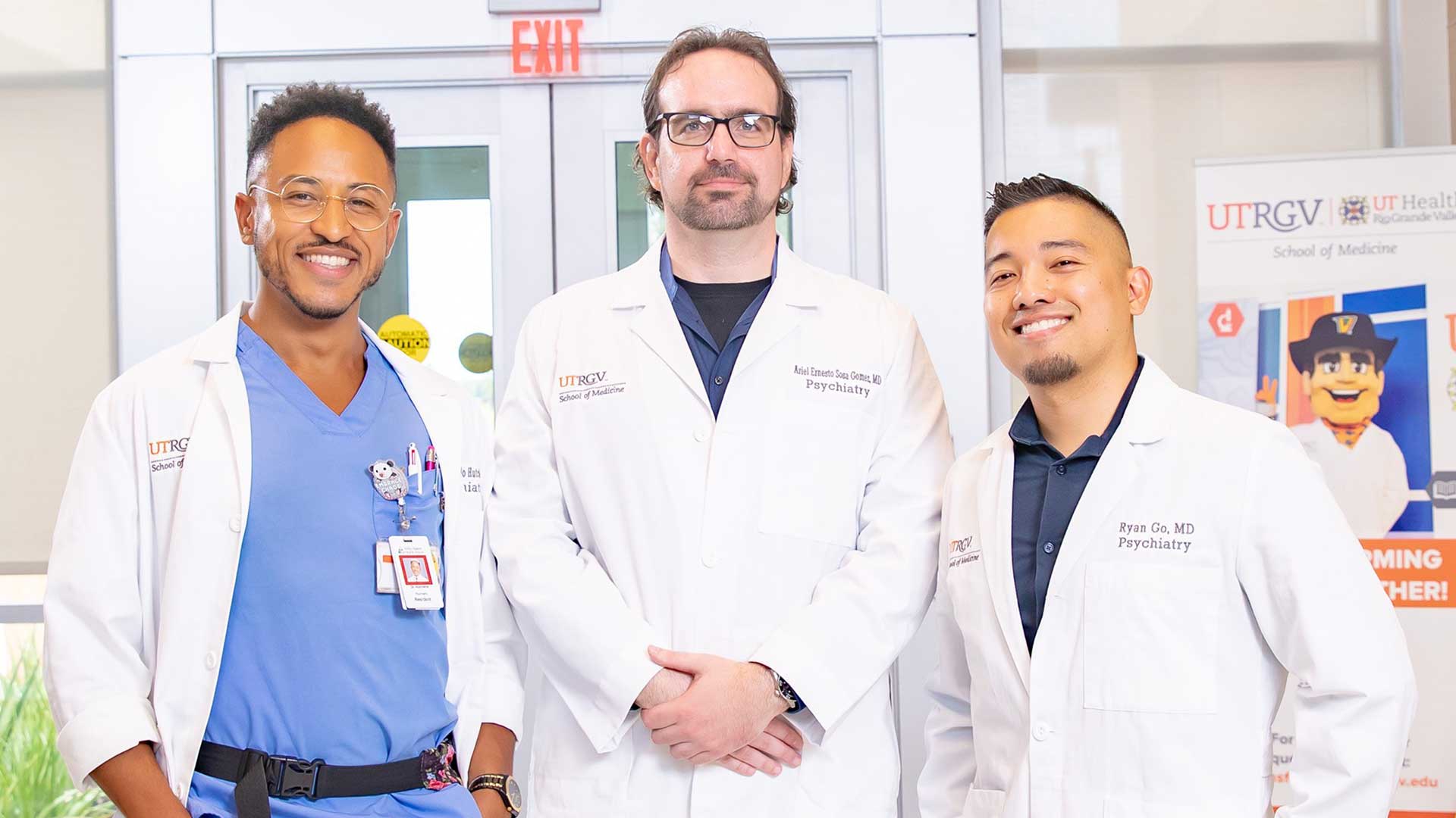Three medical professionals stand side-by-side, smiling