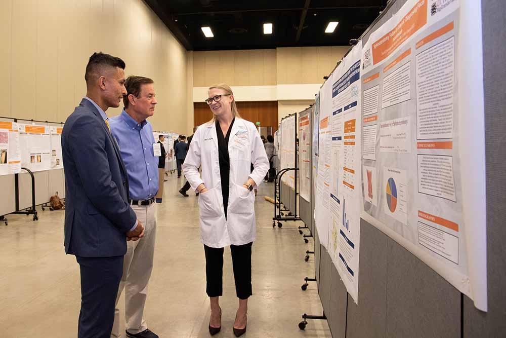 Three people discussing next to a research poster