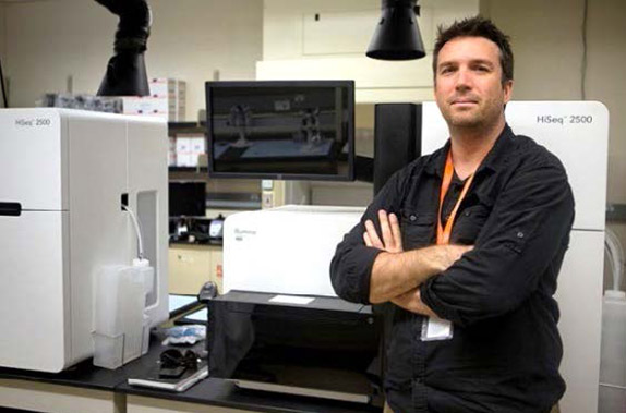 Dr. Mathew posing in front of lab equipment