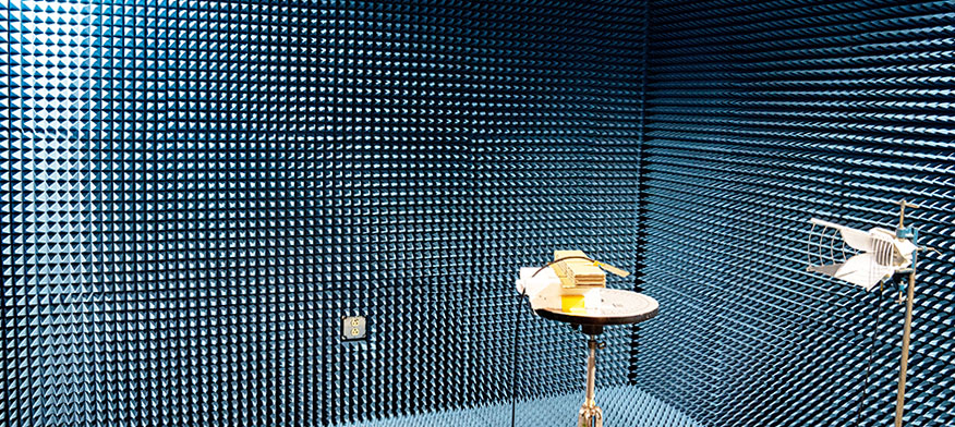 Wide angle view inside an anechoic chamber with walls made of sharp blue triangles.