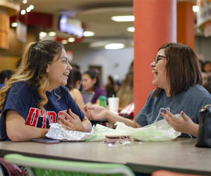 two students eating and laughing at the food court