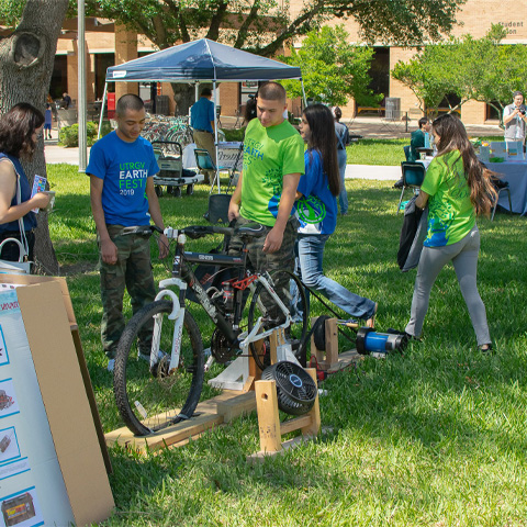 a group of students surrounding what a bike project that seems generate power