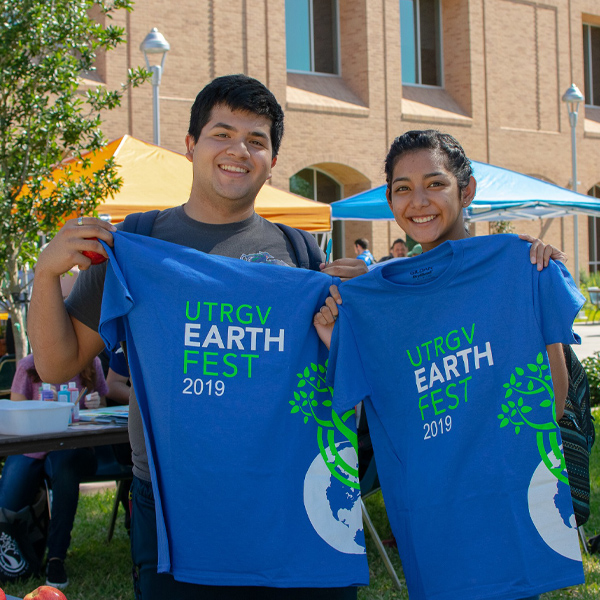 a male and female student pictured together holding up their blue utrgv earth fest tshirts that says, 'UTRGV Earth Fest 2019'