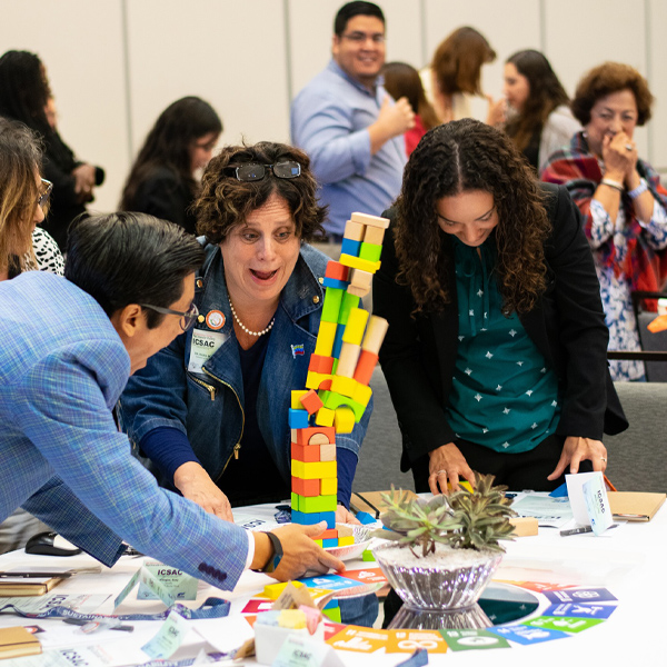a photo of a group of people playing a jenga like activity at the ICSAC Conference