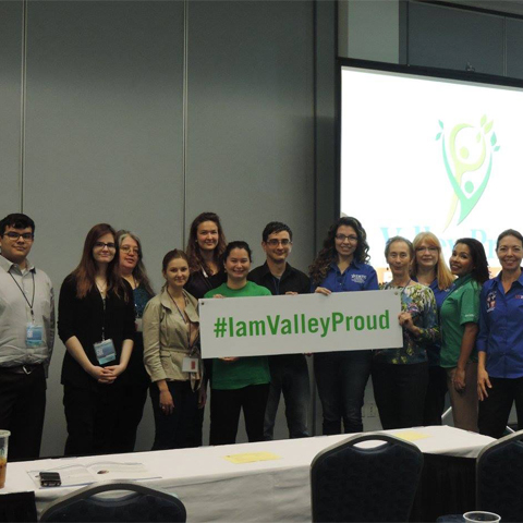 a group of people holding up a sign that says " I am Valley Proud" 
