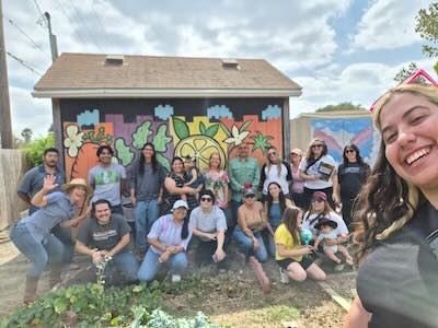 Conservationists posing for selfie in front of mural and community garden