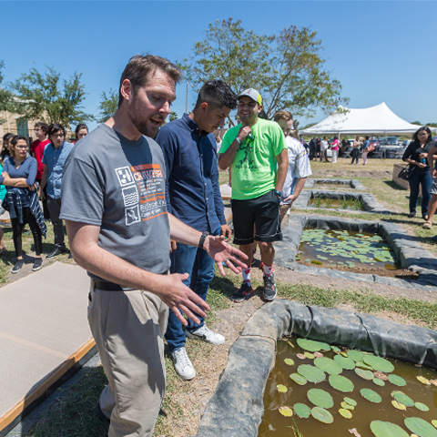 Dr. Gabler explaining the C.R.A.W.F.I.S.H. garden to students and visitors on the UTRGV Brownsville Campus behind the Casa Bella student housing.