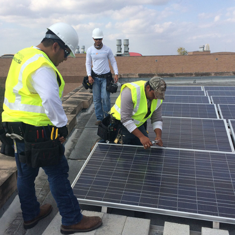 photo of men working on the rooftop solar arrays on top of UTRGV Edinburgh's Engineering Building