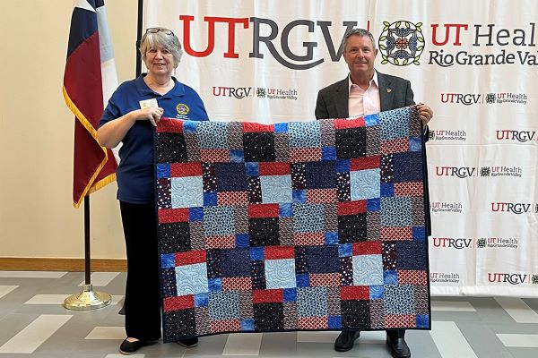 Diana Wolf, in-coming president of the RGVQG, holds a quilt with Dr. Micheal B. Hocker, dean of UTRGV SOM and senior vice president of UT Health RGV, who served as a lieutenant commander and flight surgeon in the US Navy. He was stationed with the marine aviation wing for his last active-duty assignment in Kaneohe, Hawaii. (UTRGV Photo by Karen Villarreal)