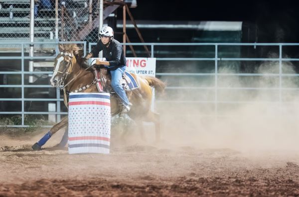 UTRGV communications major Claire Lee kicks up some dust during a barrel racing competition during a Willacy County Riders and Ropers event in July 2023. (UTRGV Photo by David Pike)