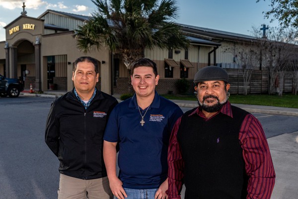 Dr. Jesus Gonzalez, Eugenio "Gene" Reyes, and Dr. Immanuel Edinbarough standing in front of the building where they installed solar panels.