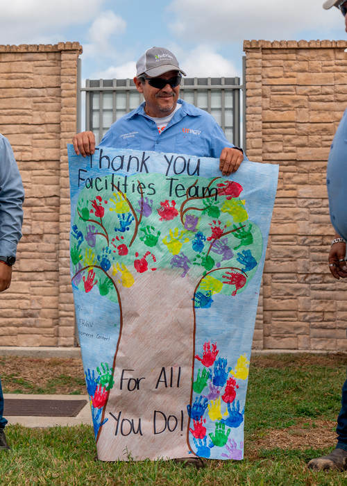 Thank You Facilities Team for All You Do Poster being held up by facilities