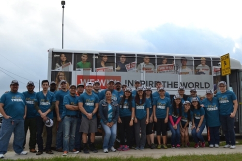 Students in front of a UTRGV buys with shirts that say plant trees and tree campus hats on