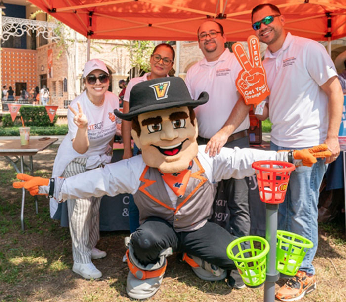 UTRGV employees posing for photo with the UTRGV Vaquero Mascot.