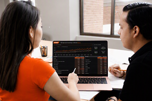 Two workers looking at an analytics dashboard on a laptop.