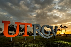 UTRGV sign with palm trees and sunrise in the background